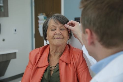 dermatologists inspects face of female patient